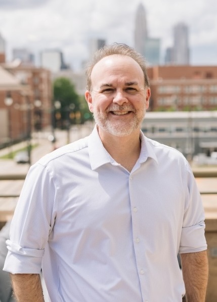 Image of Rob smiling outside with a cityscape behind him